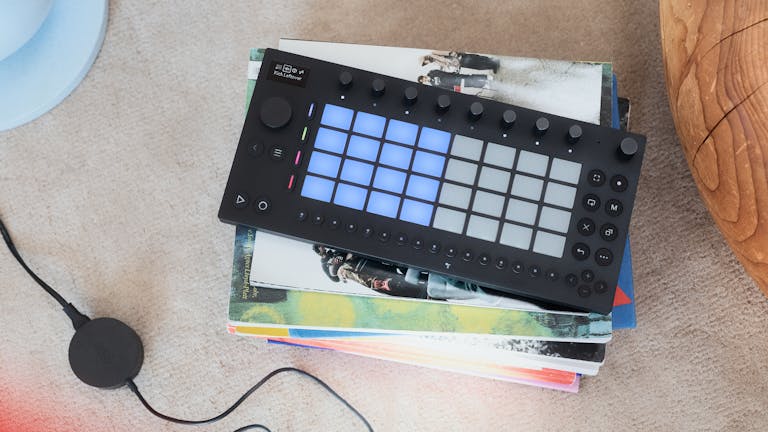 Top down view of Ableton Move lying on a pile of books. The pads are on drum mode