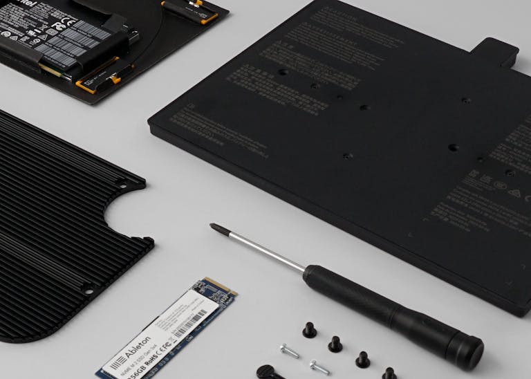The upgrade kit contents, neatly arranged on a surface – the processor, hard drive, battery and heatsink, along with a screwdriver and a variety of screws.